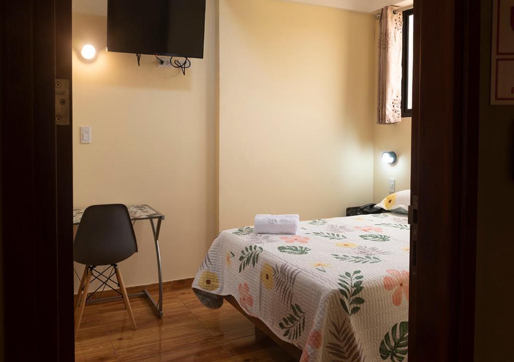 een slaapkamer met een bed, een tafel en een stoel bij Hotel Precursores in Lima