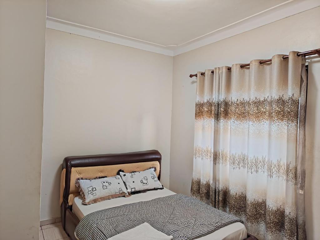 a bedroom with a bed and a curtain at Twinkle Blue Inn in Namugongo