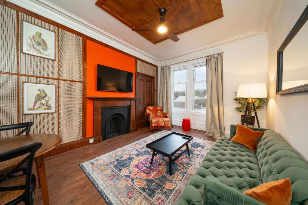 a living room with a green couch and a fireplace at Central Apartments - Colonial in Blairgowrie