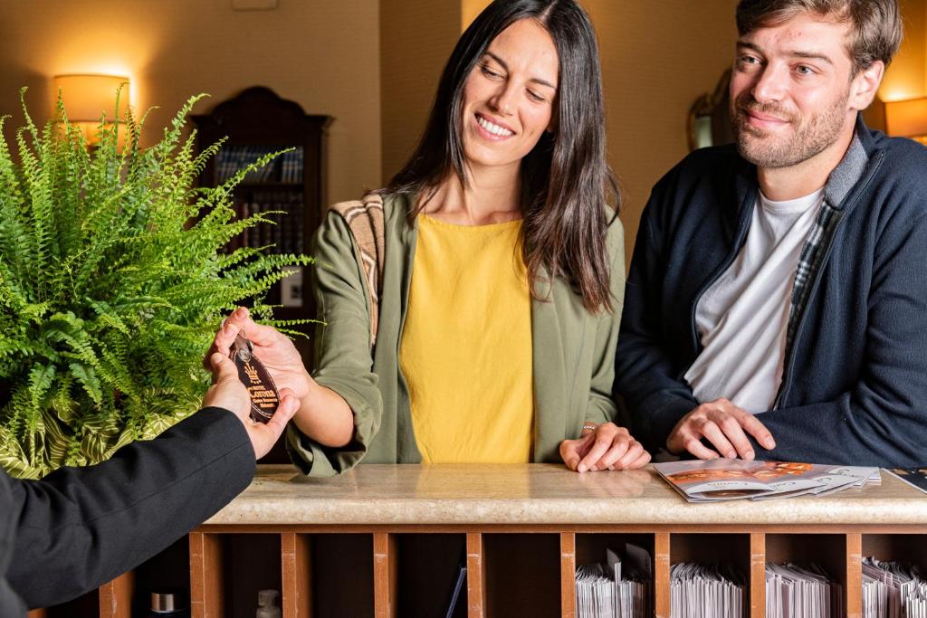 a woman and two men shaking hands over a table at Hotel Corona & Spa in Pescasseroli
