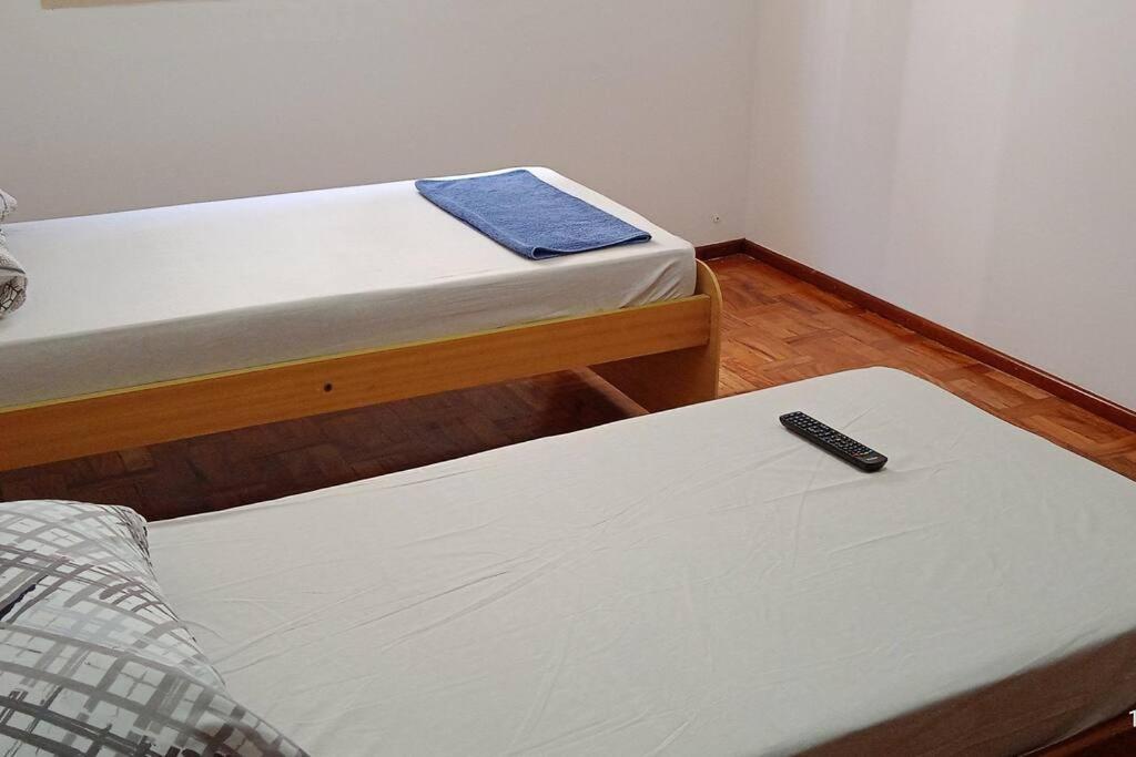 two beds in a room with a remote control on the floor at Excelente Apartamento em Área Nobre in Poços de Caldas