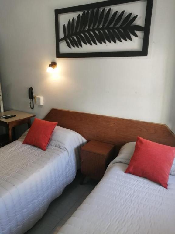 a hotel room with two beds with red pillows at Suite en Hotel Omega Palermo in Buenos Aires