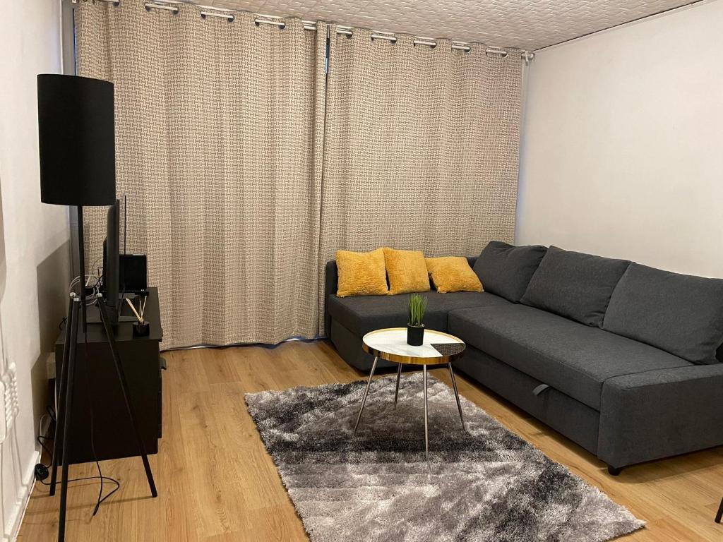 a living room with a gray couch and a table at Walk to Lcy Airport Excel Dlr 1Br Flat in London