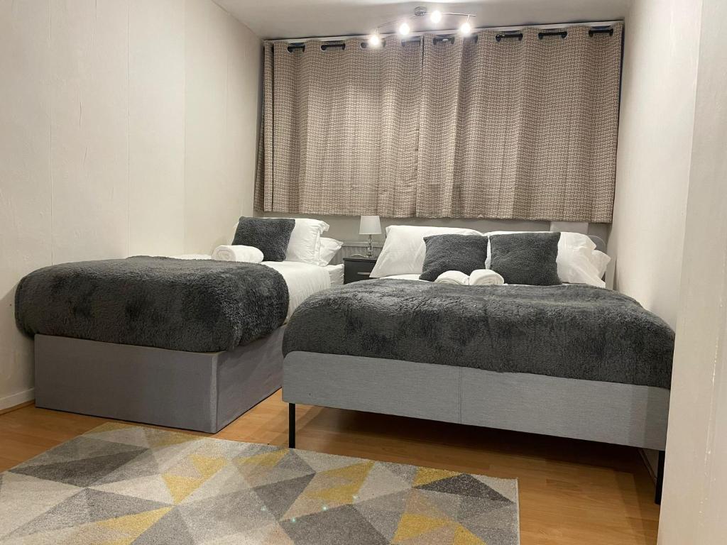 dos camas sentadas una al lado de la otra en un dormitorio en Walk to Lcy Airport Excel Dlr 1Br Flat, en Londres