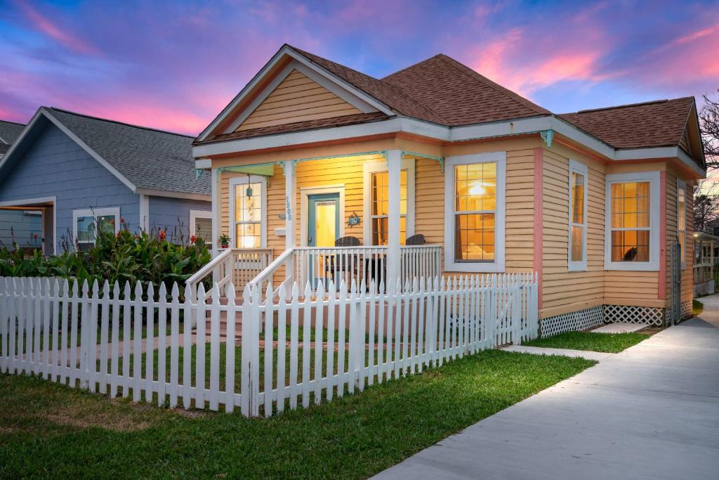 uma pequena casa com uma cerca branca em frente em Private Oasis W Two Houses 300 Steps to Beach em Galveston