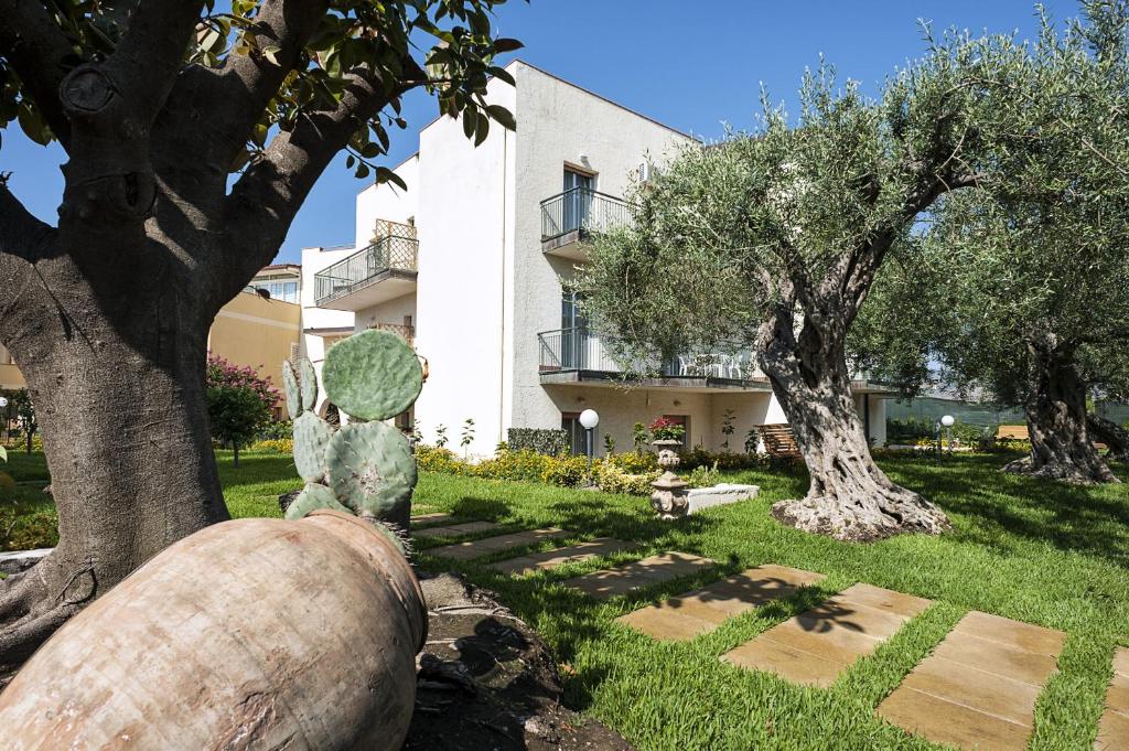 a garden with a large tree and a building at Villa Collina in Giardini Naxos