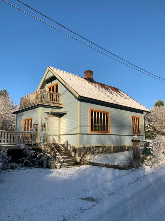 une maison blanche avec une terrasse couverte et des escaliers dans la neige dans l'établissement Swedish Quarry House, à Lönsboda