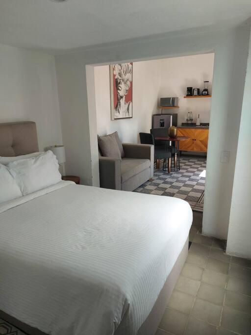 a bedroom with a white bed and a living room at Casa Monarcas - Diana (with AC) in Guadalajara