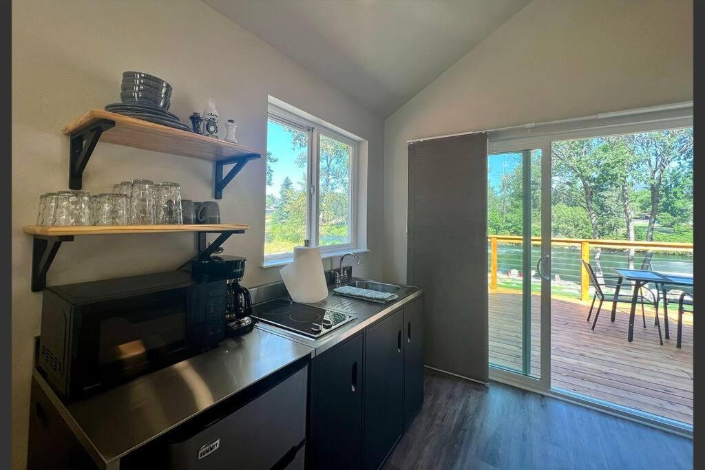 a kitchen with a stove and a balcony with a table at Loft Cabin 2 - Rogue River Resort in Grants Pass