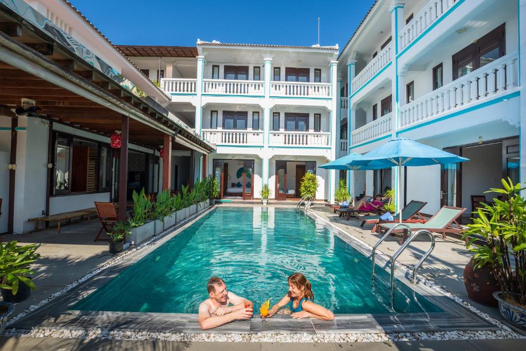 a man and a woman laying in the swimming pool of a hotel at Seagull Nest Hoi An Beach Village in Tân Thành (1)