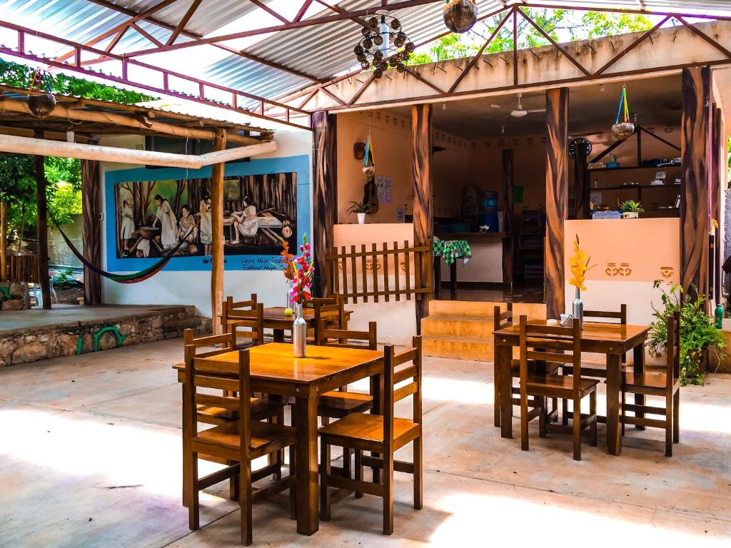Yaxche Centro Hostal y Camping في باكالار: مطعم أمامه طاولات وكراسي خشبية
