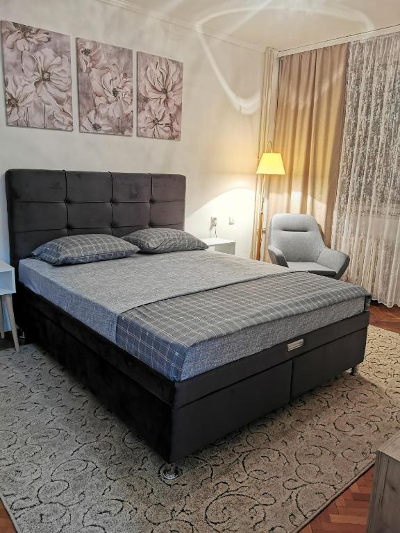 a bedroom with a large bed and a chair at Apartman Aki in Pirot