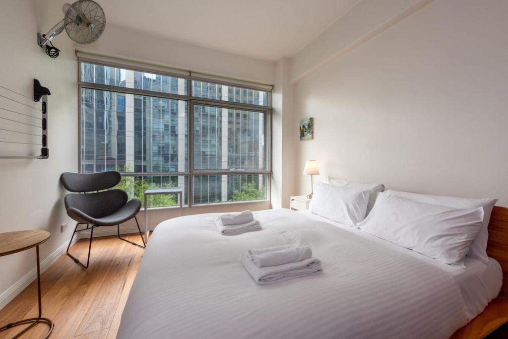 1 dormitorio con 1 cama blanca con silla y ventana en Central Studio in the Heart of Melbourne CBD!, en Melbourne