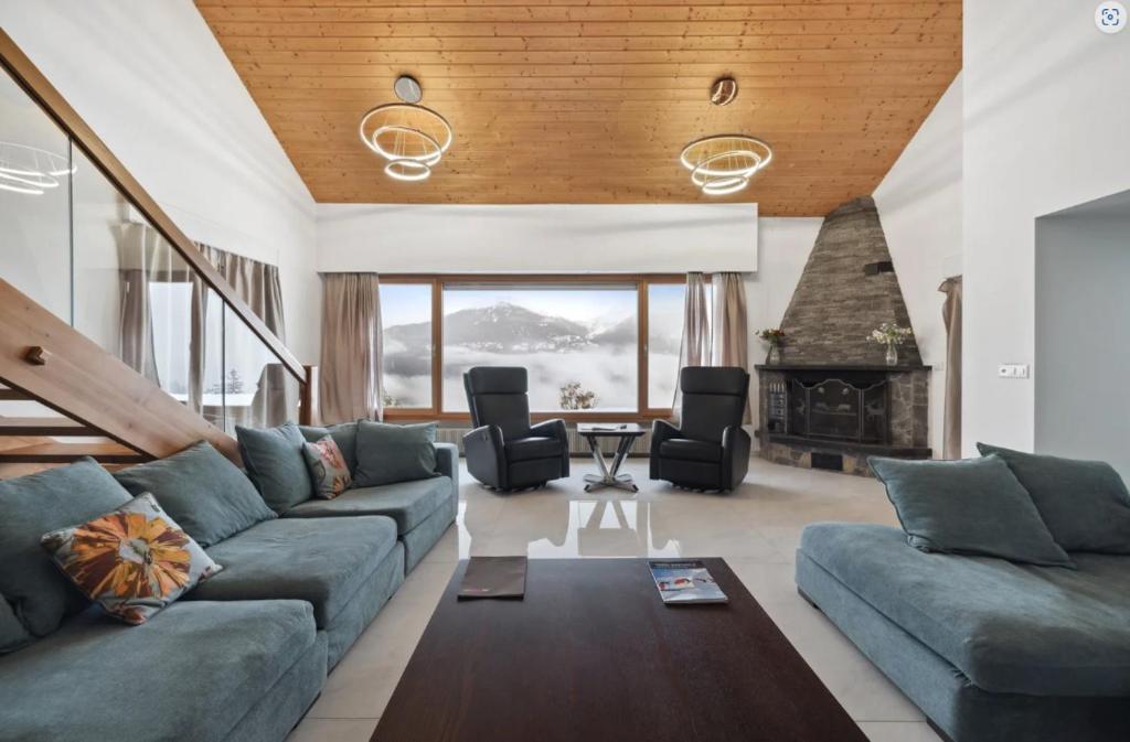 a living room with a blue couch and a fireplace at Magnificent mountain home - 756 in Crans-Montana