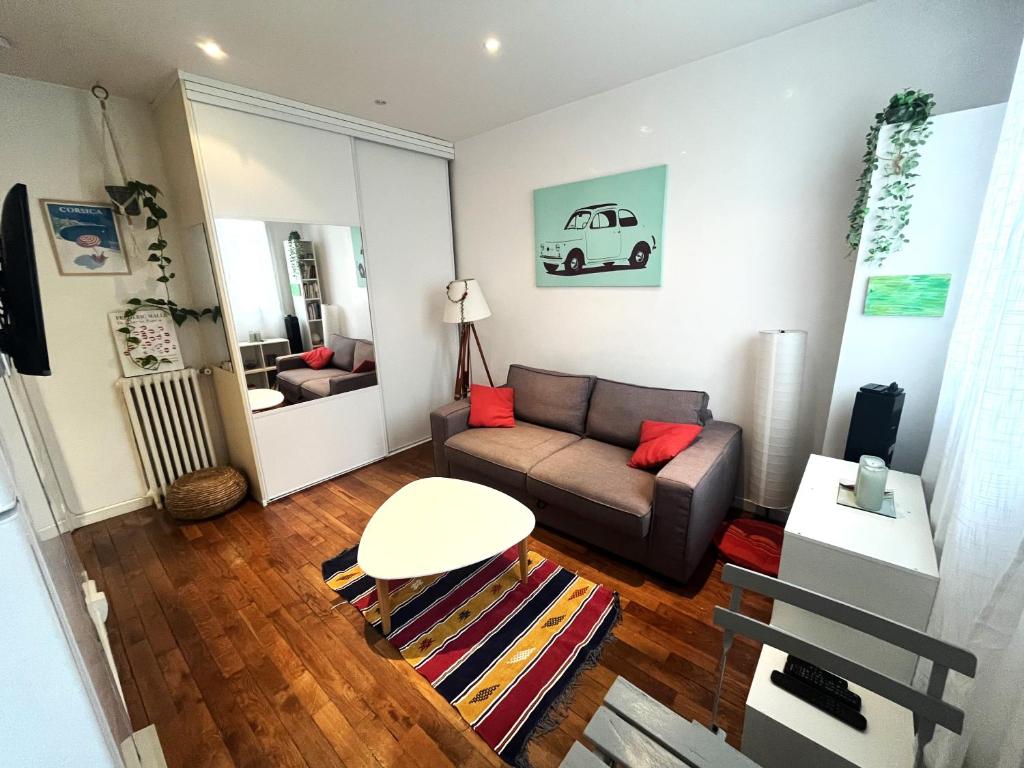 een woonkamer met een bank en een tafel bij Studio lumineux aux portes de Paris in Clichy