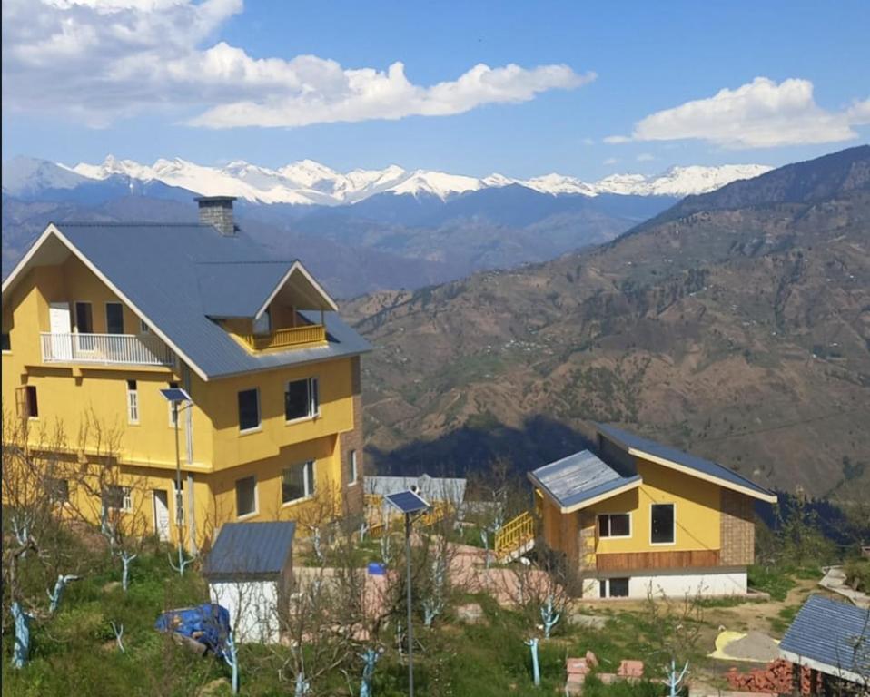 a house on a hill with mountains in the background at Forest Walk Cottage by Livingstone in Shimla