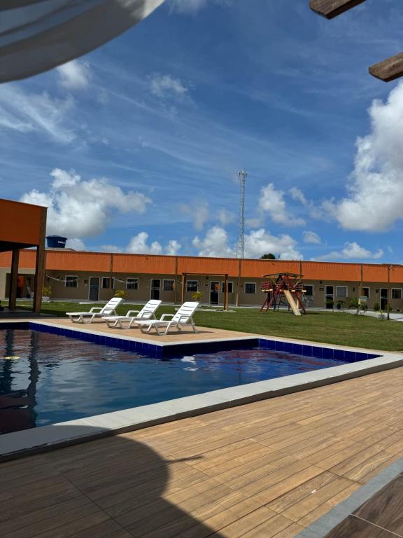 a swimming pool with lounge chairs and a playground at Pousada Vila das Lagoas in Santo Amaro