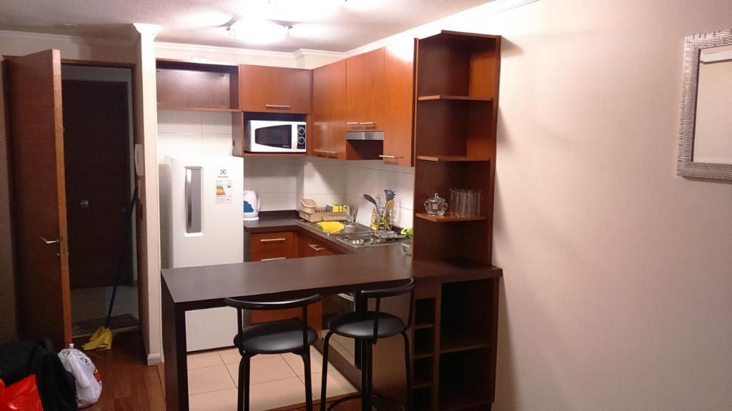 una pequeña cocina con encimera y taburetes. en Apartment Marin 80 en Santiago
