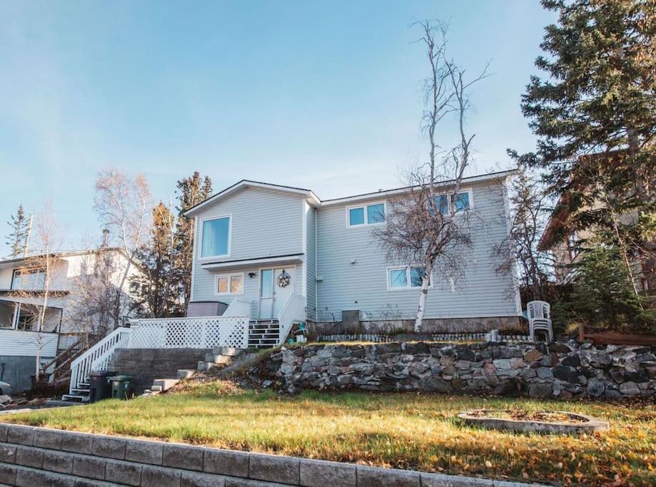 a white house with a stone wall in front of it at Yellowknife Downtown 50a avenue Retreat in Yellowknife