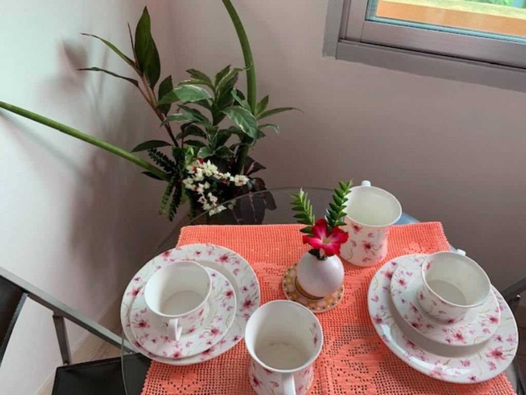 a table with three cups and plates on a table at Phuket Latika Mansion by Andaman Home in Phuket Town