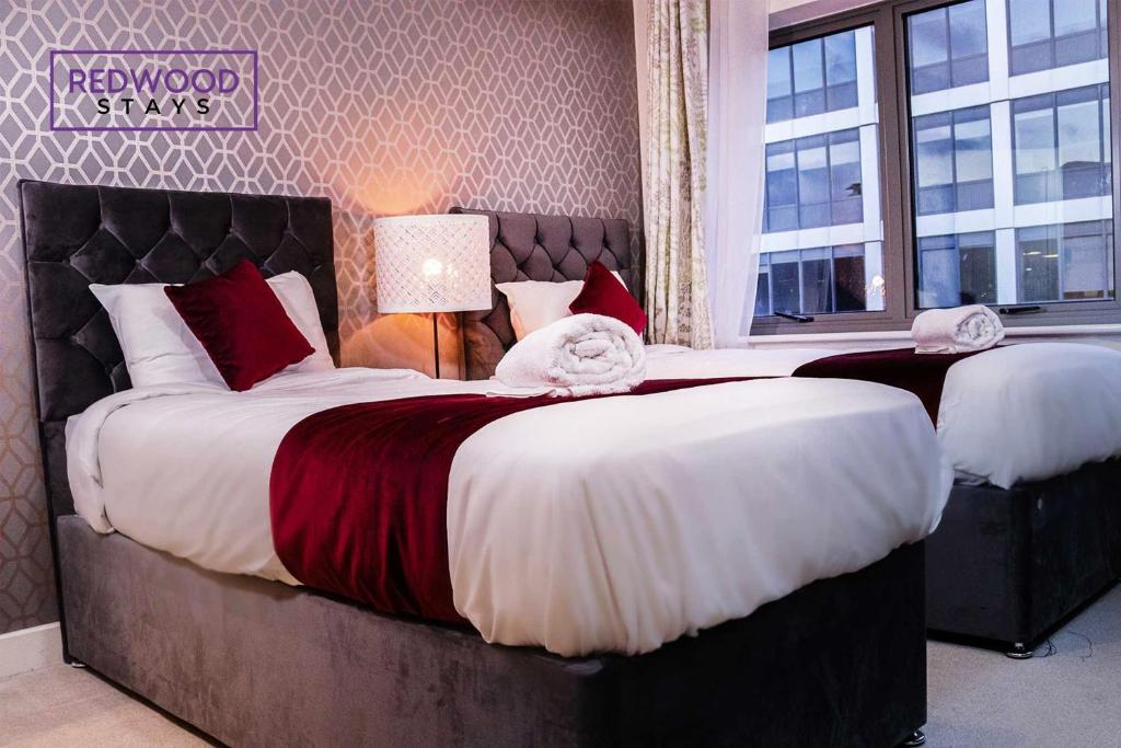een slaapkamer met 2 bedden met rode en witte kussens bij Festival Place, Modern Town Center Apartment, Perfect for Contractors & Families, FREE Parking & WiFi by REDWOOD STAYS in Basingstoke