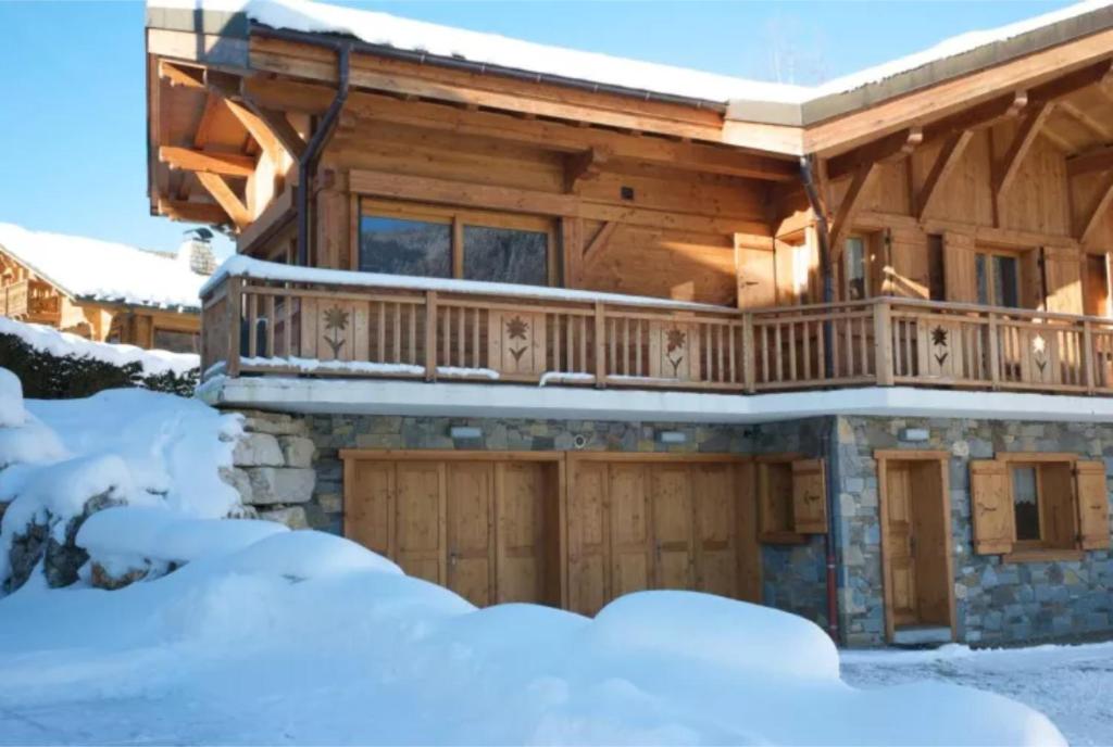 a log home with a deck in the snow at Chalet L'aube claire - 5 étoiles in Morzine