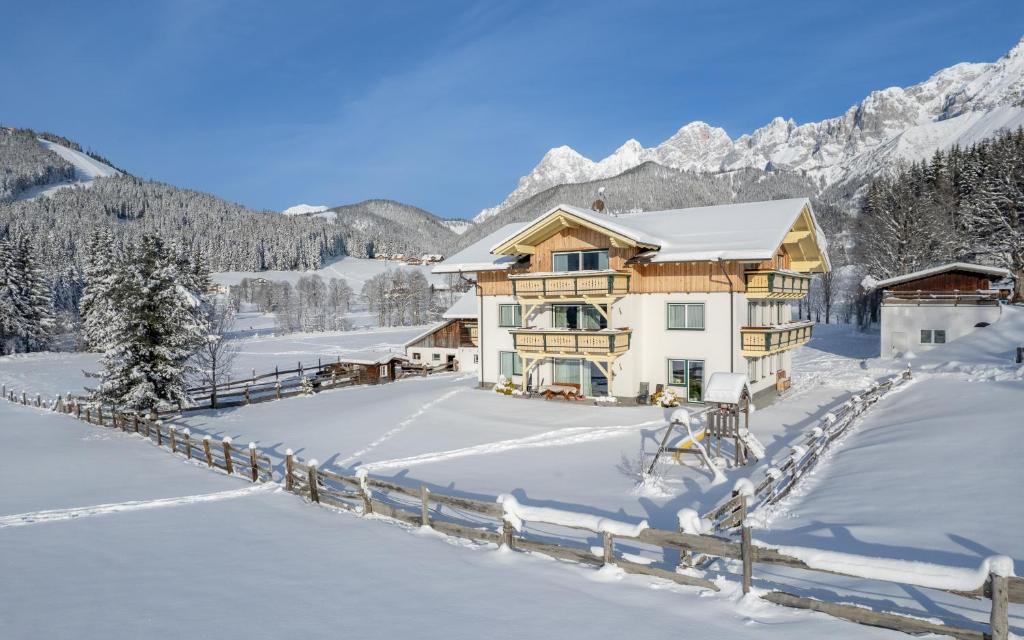 una casa en la nieve con montañas en el fondo en Luxus-Appartements Fosensteiner en Ramsau am Dachstein