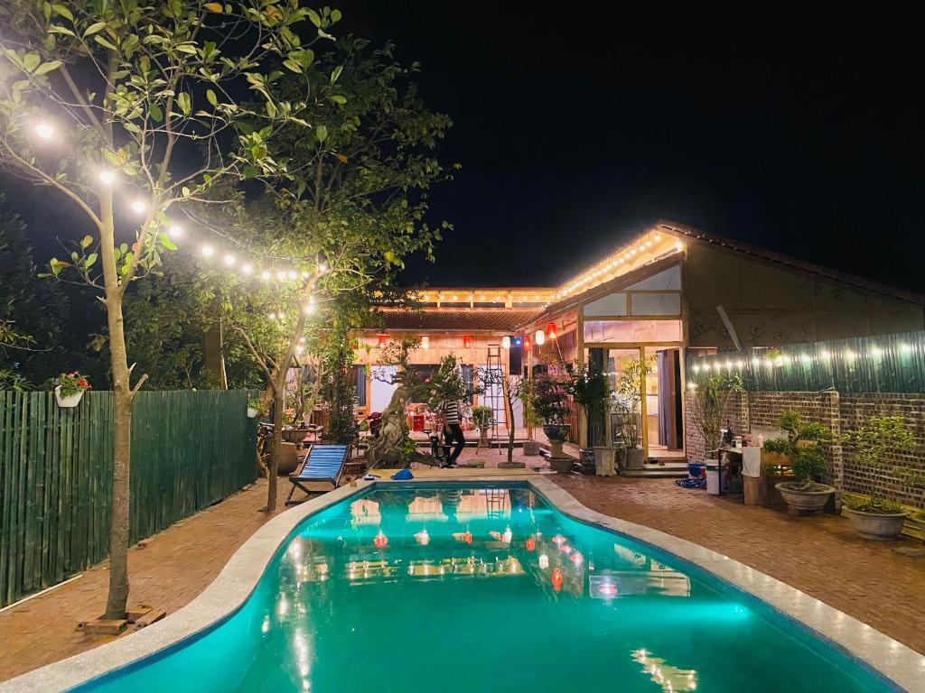 a swimming pool in front of a house at night at An Homestay Tam Coc in Ninh Binh