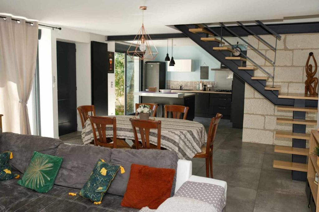 ein Wohnzimmer mit einem Tisch und eine Küche mit einer Treppe in der Unterkunft Belle Maison tourangelle pour 6 personnes in Chambourg-sur-Indre