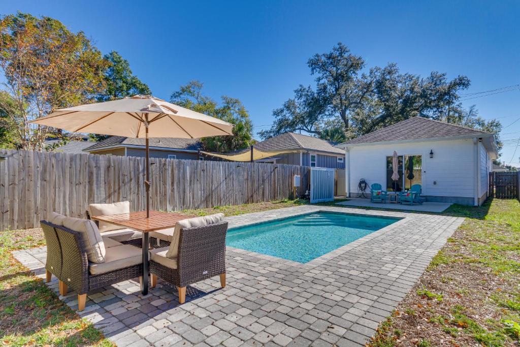 a table with an umbrella and chairs next to a pool at Modern Pensacola Vacation Home with Private Pool! in Pensacola