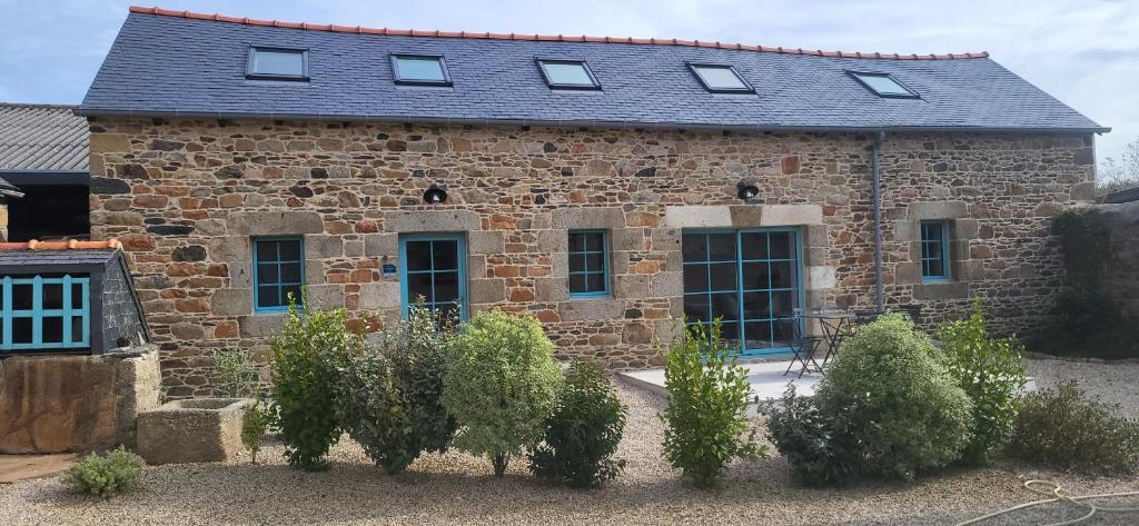 un antiguo edificio de piedra con ventanas y arbustos delante en Gîte Paimpol Le Loarwenn, en Paimpol