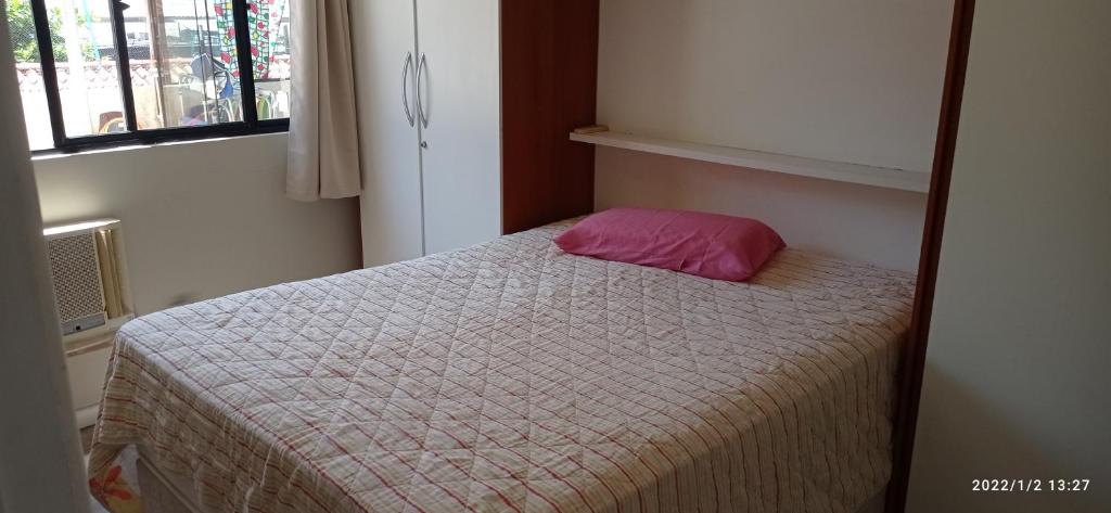 una piccola camera da letto con letto e cuscino rosa di Apartamento meia praia a Itapema