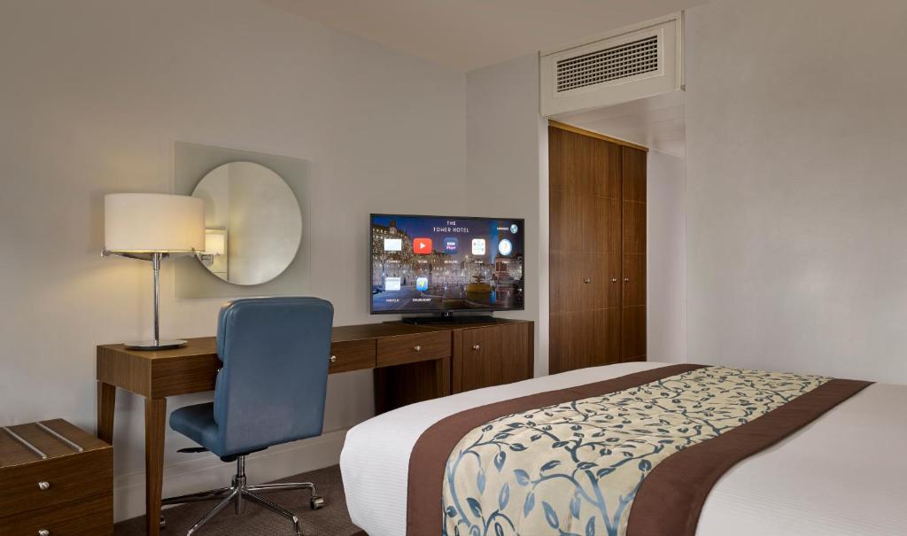 a hotel room with a bed and a desk and a television at The Tower Hotel, by Thistle in London