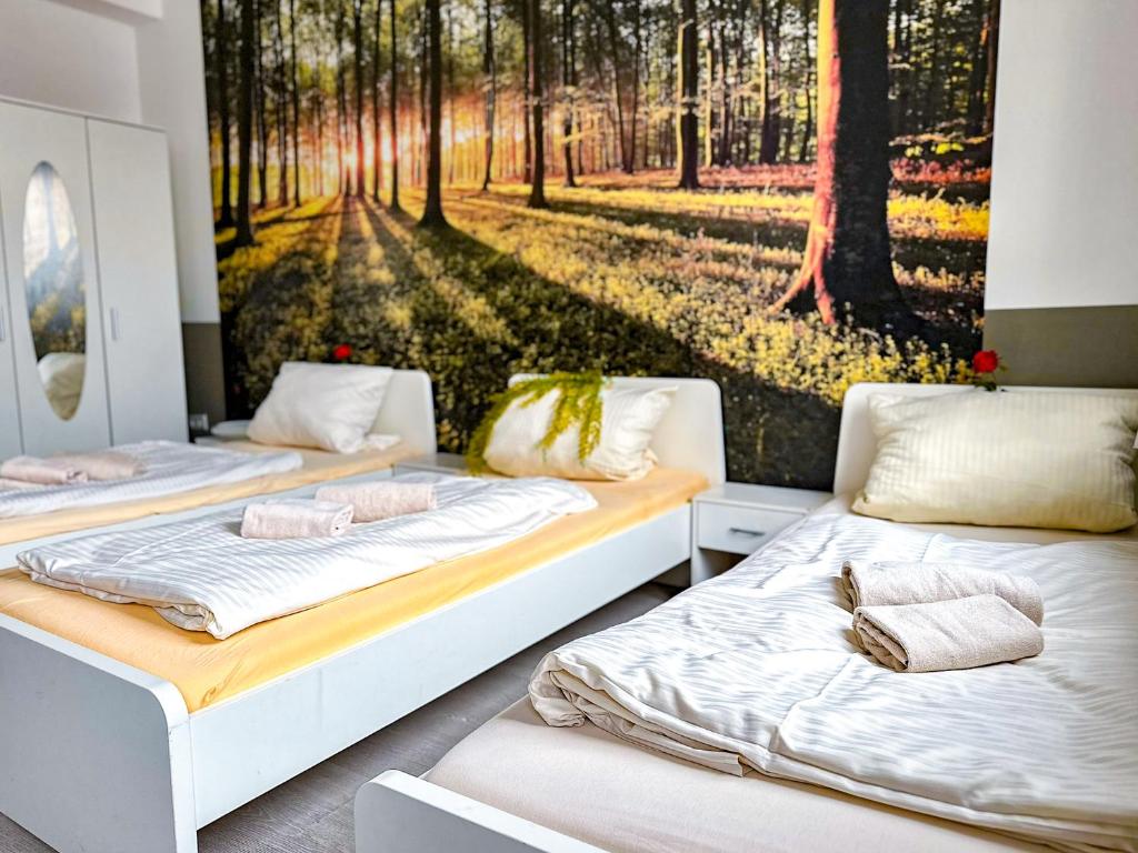 two beds in a room with a picture of a forest at Pension MC City in Gaimersheim