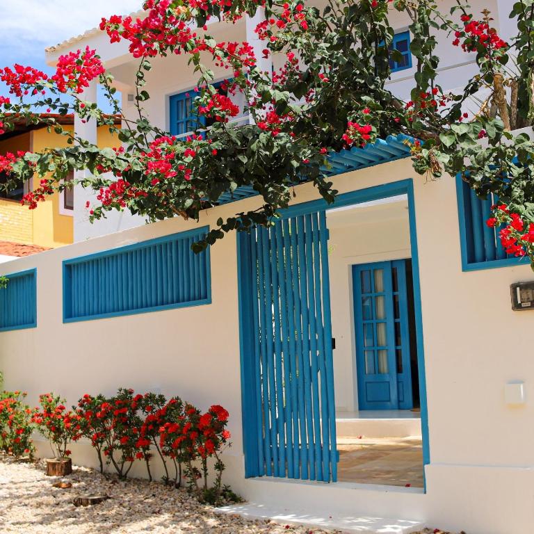 a blue door on a white building with red flowers at Vila Marinella in Jericoacoara