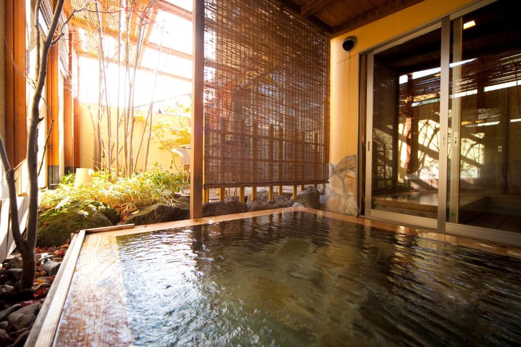 a swimming pool in front of a house at Kutsurogi-no-Yado Nanakawa in Yufuin