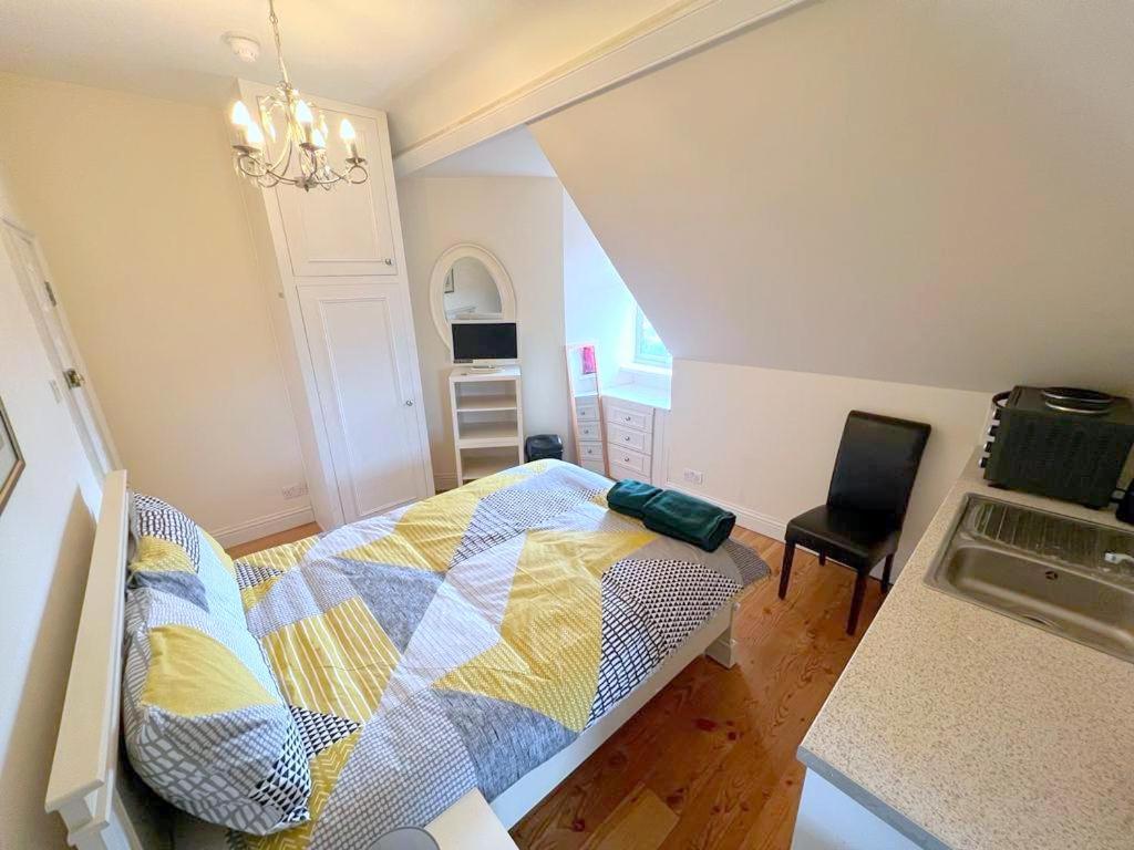 Schlafzimmer mit einem Bett und einem Kronleuchter in der Unterkunft Sutton Studio Apartments in Cheam