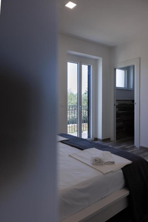 a white bedroom with a bed and a large window at Essentia Rooms & Relax in Vasto