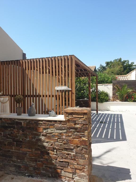 a patio with a stone wall and a wooden structure at Appartement LE BOIS FLOTTE in Saintes-Maries-de-la-Mer