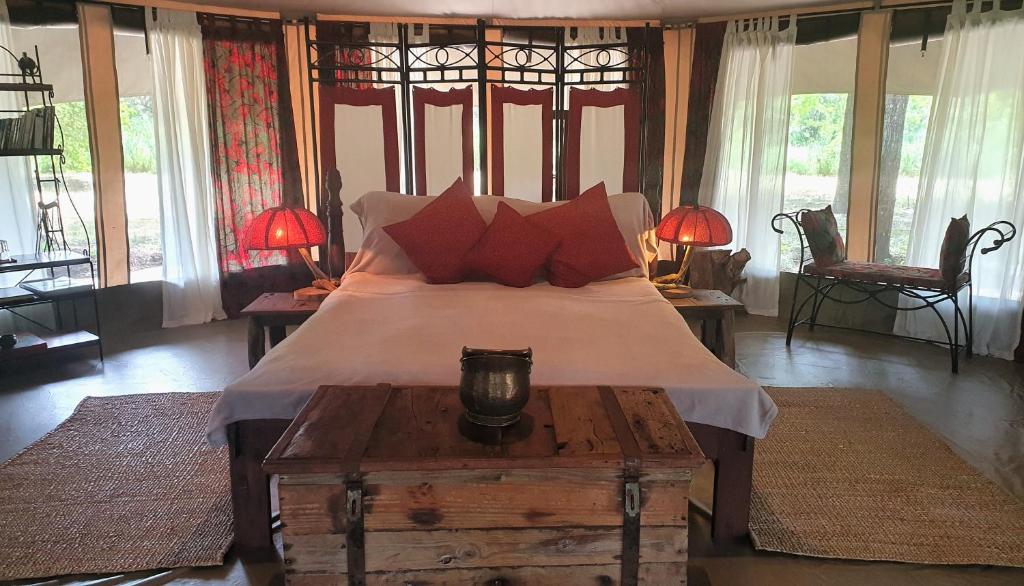 a bedroom with a large bed with red pillows at Family Tent - Dolly Farm & River Camp in Usa River