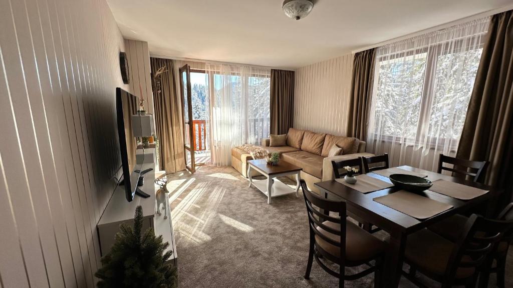 a living room with a table and a couch at ELEA Apartment Mountain Lodge Pamporovo in Pamporovo