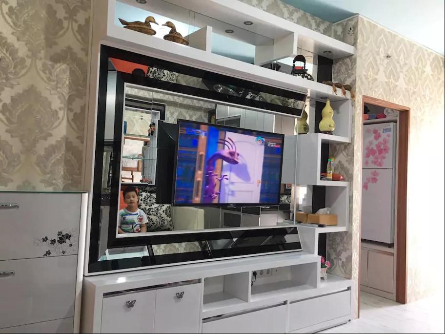 una sala de estar con TV en un centro de entretenimiento blanco en kemah uwuh en Kalianget