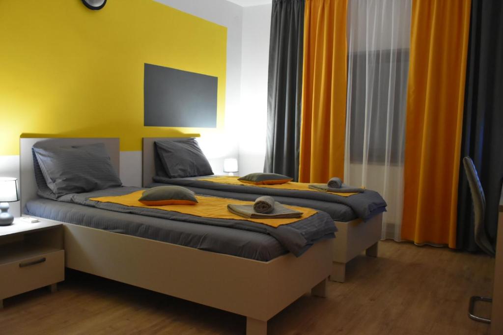 a bedroom with two beds with yellow walls at Casa Novis in Băicoi