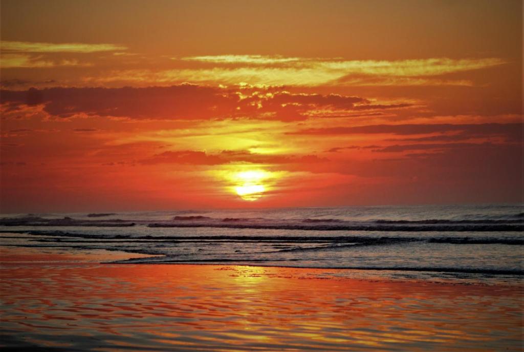 zachód słońca na plaży z oceanem w obiekcie Suítes Libertah w mieście Peruíbe