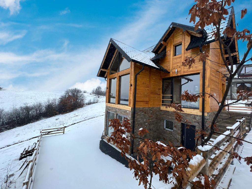 una casa de madera en la nieve con un arco iris en LUX PINE house en Zlatibor