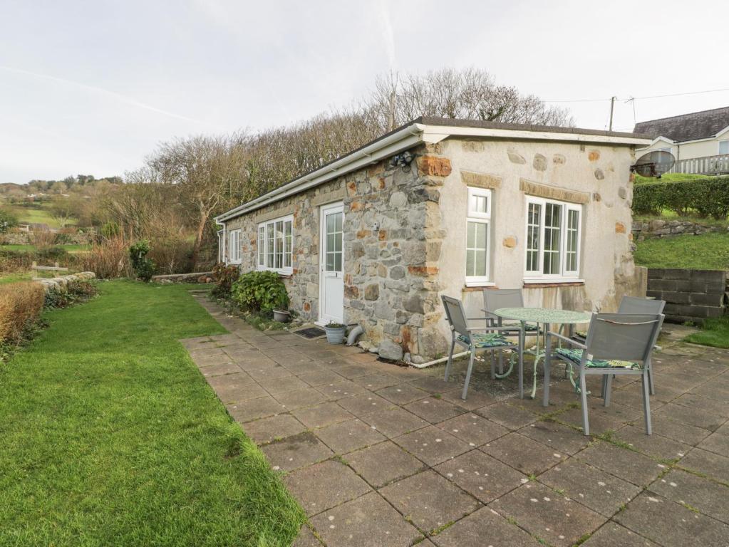 a stone cottage with a table and chairs in front of it at Hen Felin Isaf in Llanddona