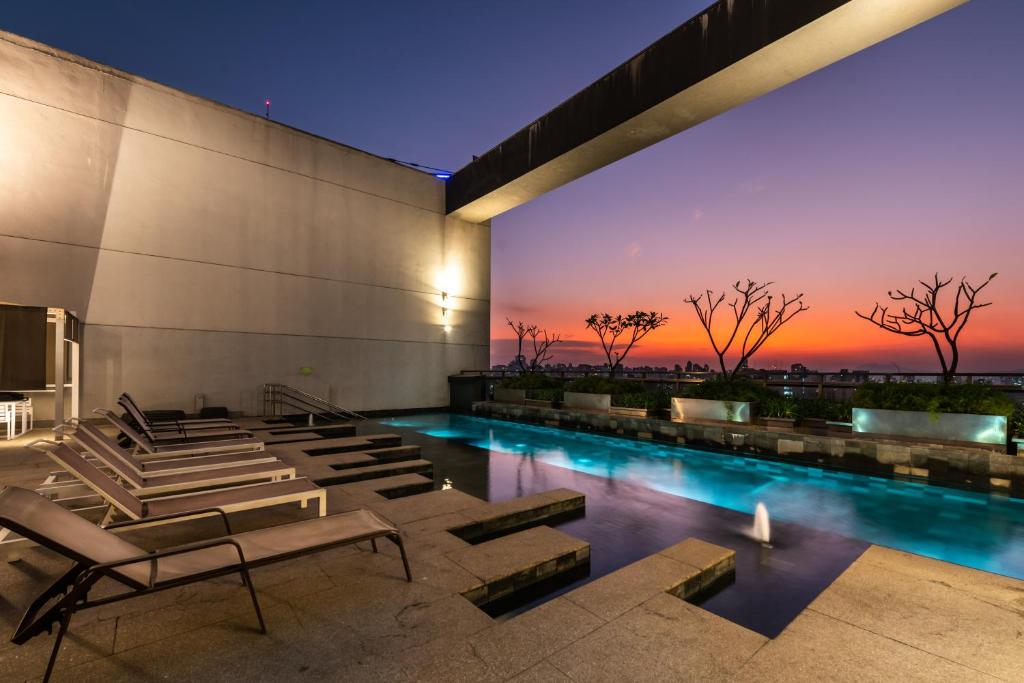 a building with a swimming pool with a sunset at Rosemari's Apartments Republica in Sao Paulo