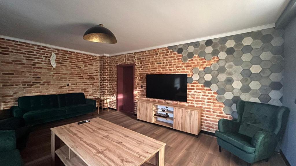 a living room with a tv and a brick wall at IZERSKI TARAS- Górski Apartament 120m2 in Świeradów-Zdrój