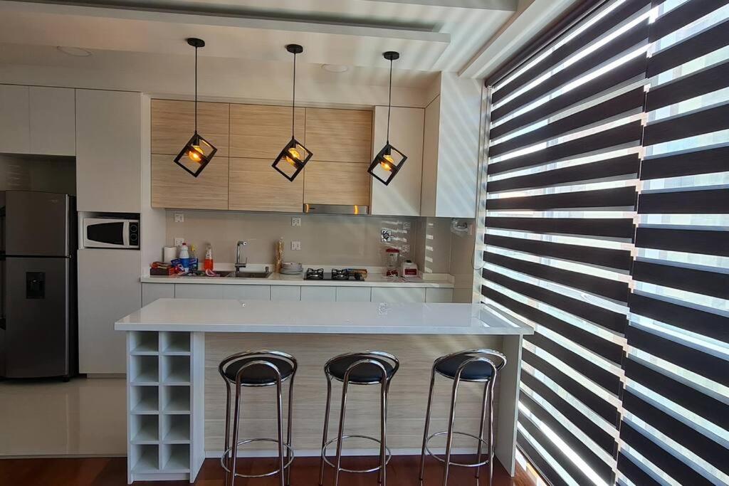 拉巴斯的住宿－departamento de 2 dormitorios，厨房配有带三把凳的柜台
