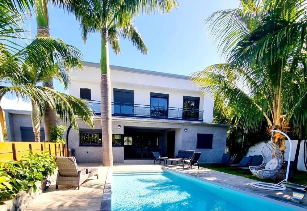 une maison avec une piscine et des palmiers dans l'établissement Villa Fleur de Coco - 8p. - piscine privée - haut standing, à Saint-Pierre